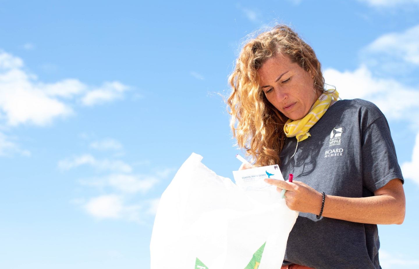 A PWF board member writes down notes while holding a plastic bag to collect marine debris in.